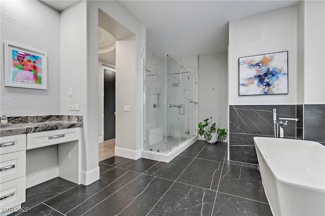 bathroom featuring vanity, independent shower and bath, and tile walls