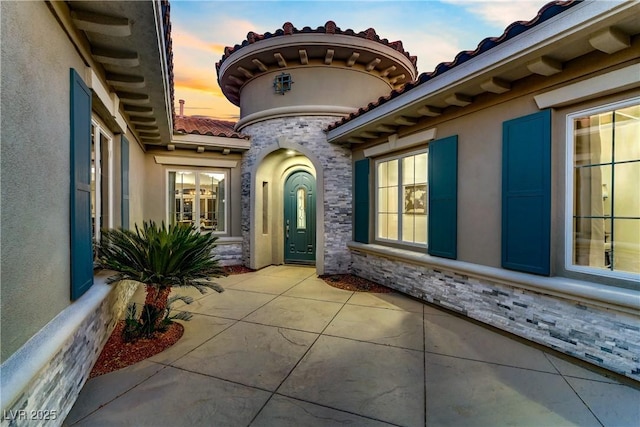 exterior entry at dusk featuring a patio area