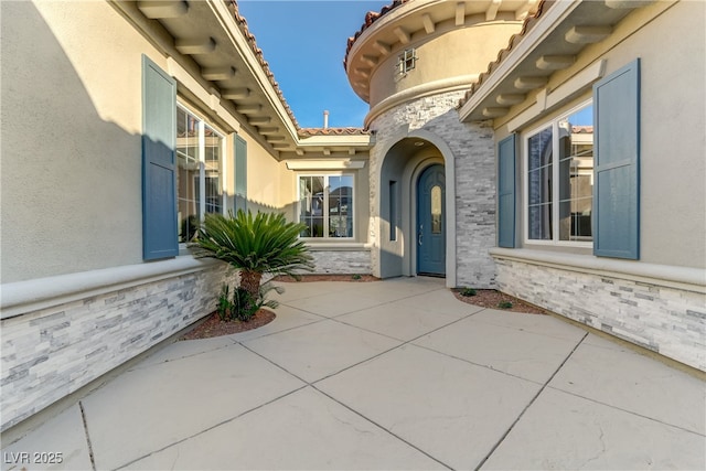 view of exterior entry with a patio area