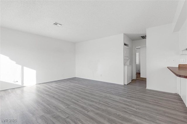 unfurnished living room featuring a textured ceiling and dark hardwood / wood-style floors