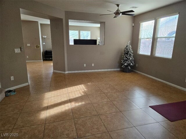 tiled spare room featuring ceiling fan and a healthy amount of sunlight