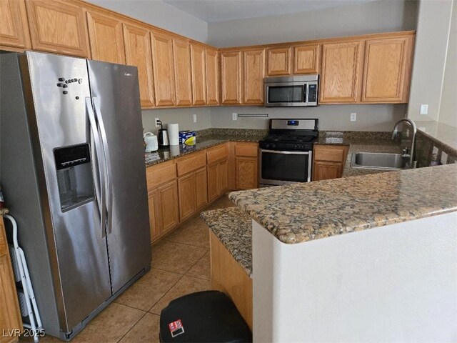 kitchen with light tile patterned flooring, appliances with stainless steel finishes, stone counters, and sink