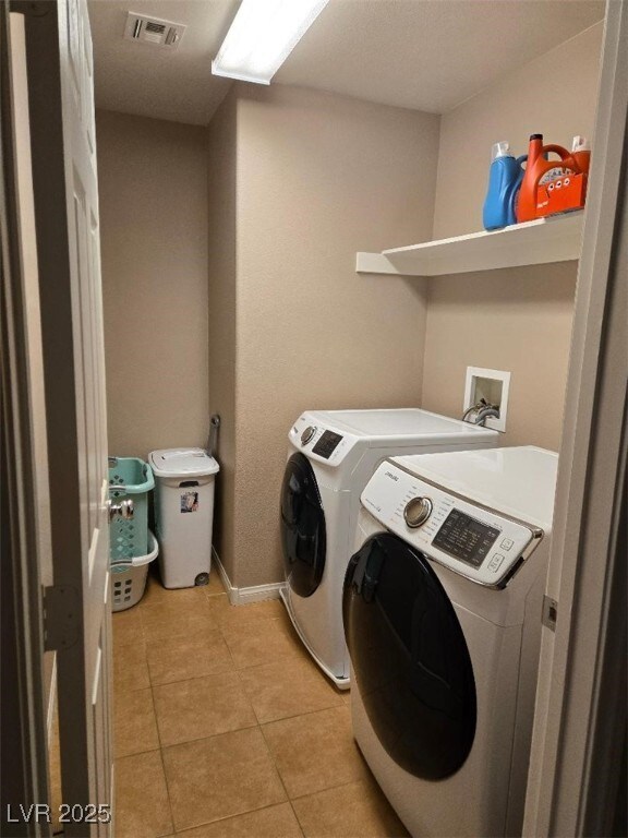 washroom with separate washer and dryer and light tile patterned floors