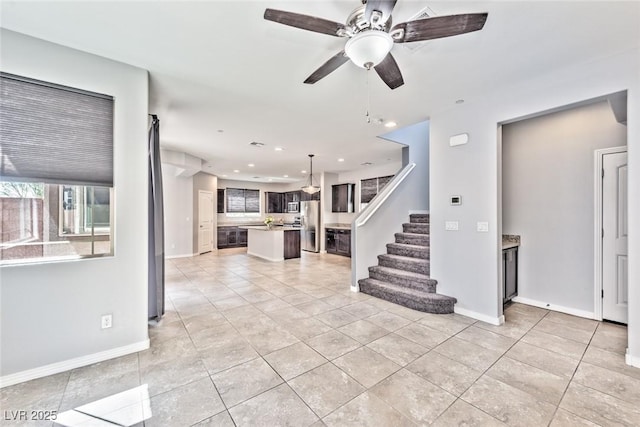 unfurnished living room featuring stairs, light tile patterned floors, ceiling fan, baseboards, and recessed lighting