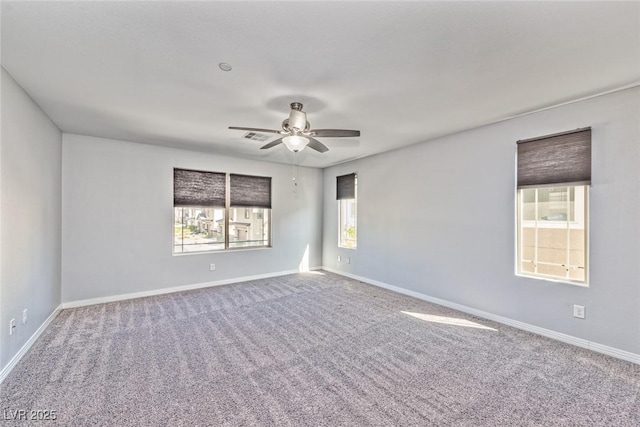 carpeted empty room with baseboards, a ceiling fan, and visible vents
