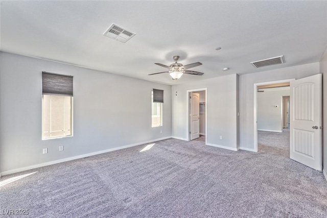 unfurnished bedroom with a spacious closet, visible vents, carpet flooring, and baseboards