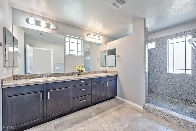 bathroom featuring baseboards, a sink, a walk in shower, and double vanity