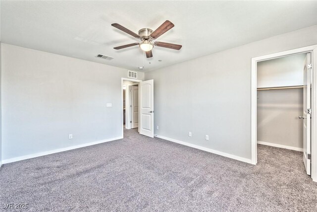 unfurnished bedroom featuring a walk in closet, carpet floors, and ceiling fan