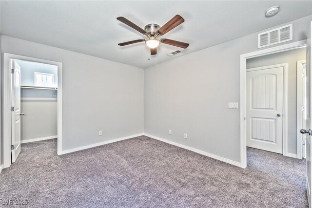 unfurnished bedroom with carpet, a spacious closet, ceiling fan, and a closet