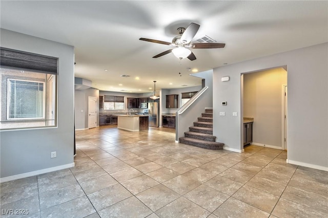 unfurnished living room with ceiling fan, sink, and light tile patterned floors