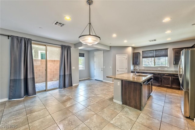 kitchen featuring freestanding refrigerator, visible vents, dark brown cabinetry, and a sink