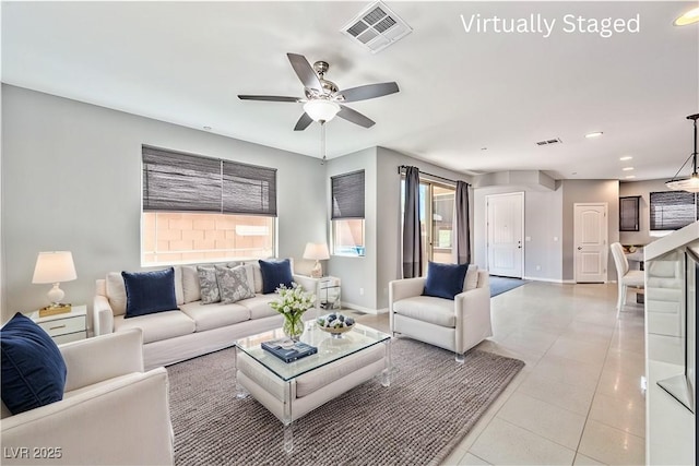 living room featuring ceiling fan, baseboards, visible vents, and light tile patterned floors