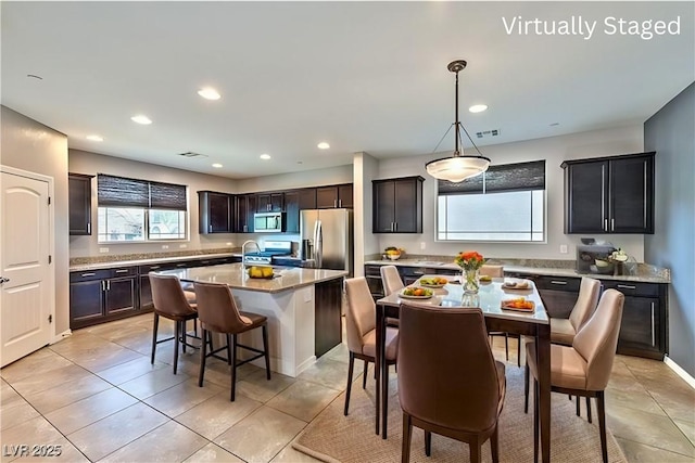 kitchen featuring a healthy amount of sunlight, light tile patterned floors, a center island, appliances with stainless steel finishes, and a breakfast bar area
