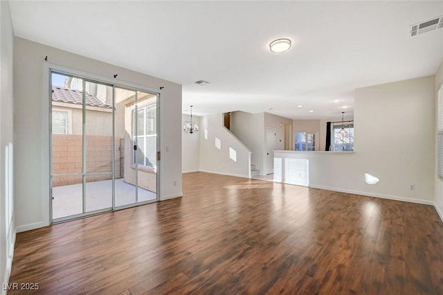 unfurnished room with plenty of natural light, a chandelier, and hardwood / wood-style flooring