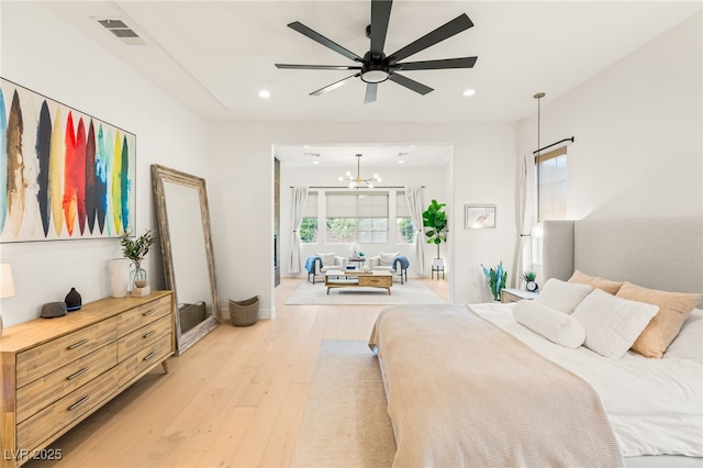 bedroom with light hardwood / wood-style flooring and ceiling fan with notable chandelier