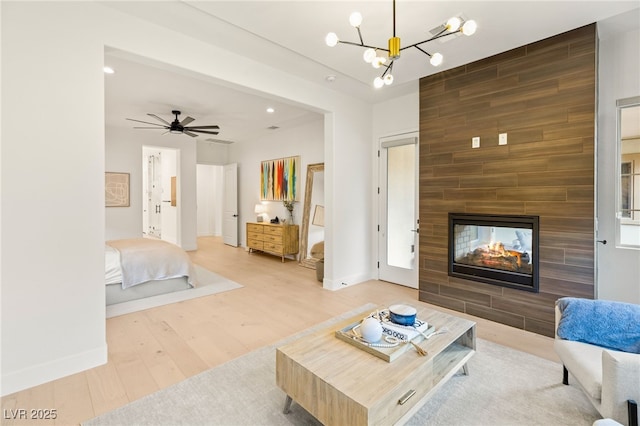 living room featuring a multi sided fireplace, hardwood / wood-style floors, and ceiling fan with notable chandelier