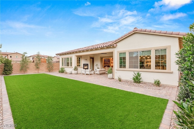 back of house featuring a lawn, an outdoor living space, ceiling fan, and a patio area