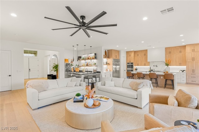 living room with light hardwood / wood-style floors, ceiling fan, and sink