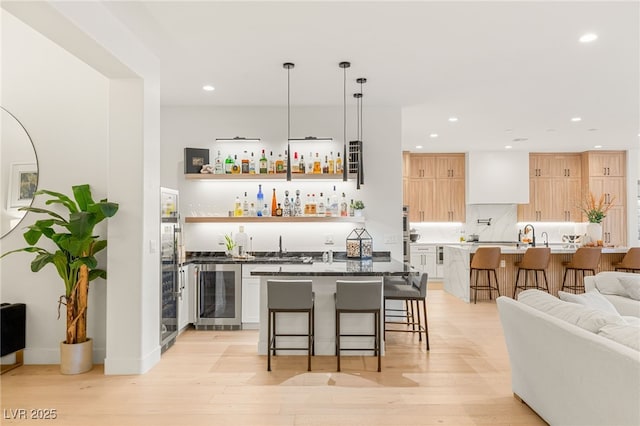 bar with wine cooler, white cabinetry, light hardwood / wood-style flooring, and pendant lighting