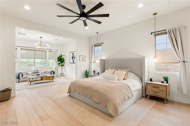 bedroom featuring ceiling fan with notable chandelier, wood-type flooring, and multiple windows