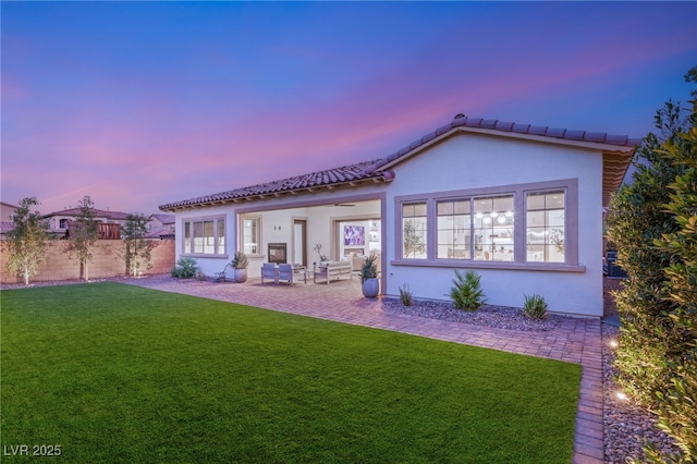 back house at dusk with a yard and a patio