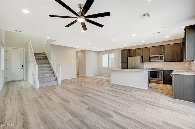 kitchen with sink, ceiling fan, light wood-type flooring, appliances with stainless steel finishes, and a kitchen island