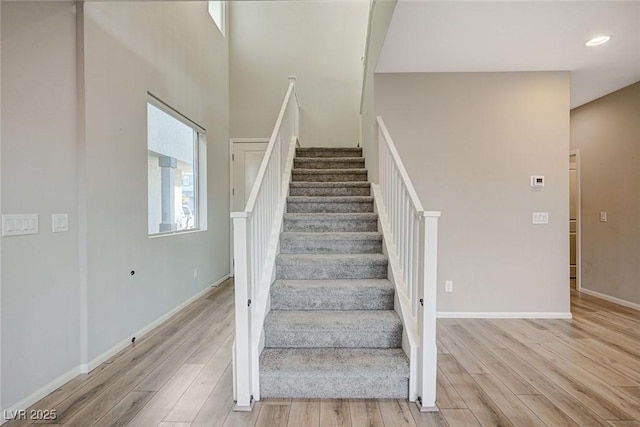 stairway featuring wood-type flooring and a high ceiling