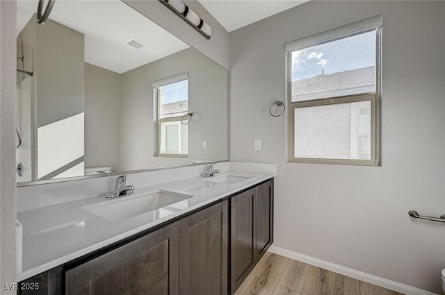 bathroom featuring vanity, toilet, wood-type flooring, and a wealth of natural light