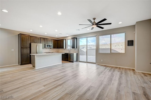 kitchen with ceiling fan, a center island, appliances with stainless steel finishes, and light hardwood / wood-style flooring