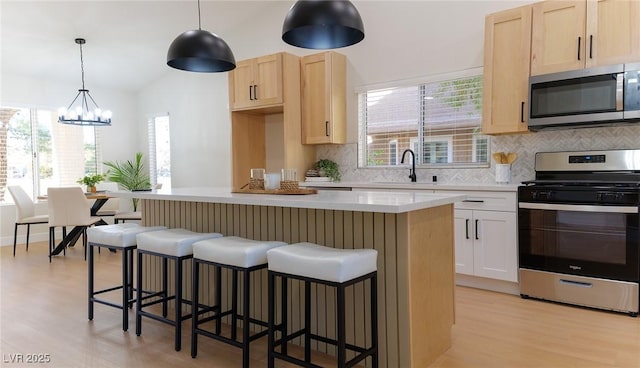 kitchen with pendant lighting, a center island, sink, appliances with stainless steel finishes, and a chandelier