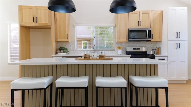 kitchen with light brown cabinetry, backsplash, and appliances with stainless steel finishes