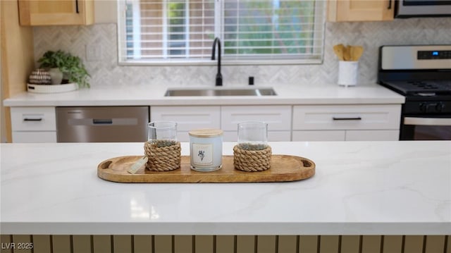 kitchen featuring white cabinets, appliances with stainless steel finishes, backsplash, and sink