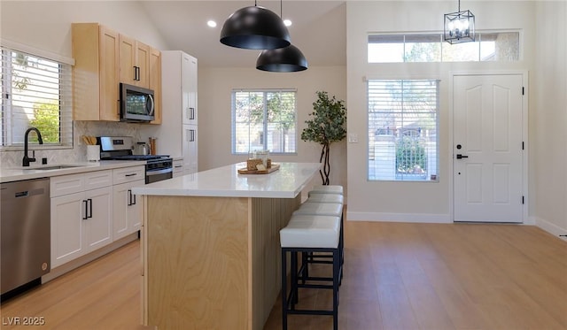 kitchen with a center island, sink, hanging light fixtures, a breakfast bar area, and stainless steel appliances