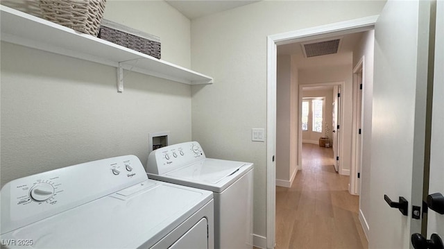 washroom featuring washing machine and dryer and light hardwood / wood-style floors