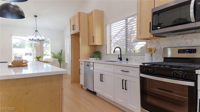 kitchen with tasteful backsplash, stainless steel appliances, sink, a chandelier, and hanging light fixtures