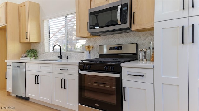 kitchen featuring white cabinetry, sink, light hardwood / wood-style flooring, decorative backsplash, and appliances with stainless steel finishes