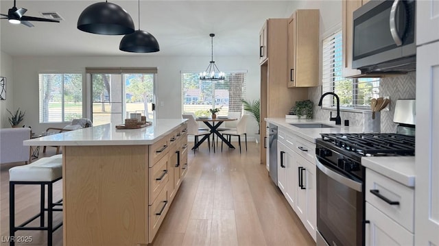 kitchen featuring sink, a center island, stainless steel appliances, pendant lighting, and decorative backsplash