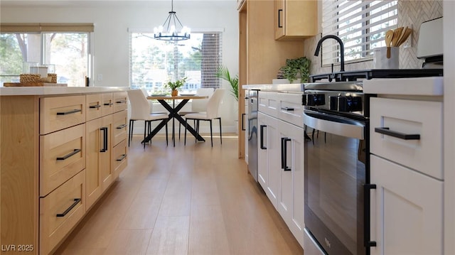 kitchen with decorative light fixtures, light wood-type flooring, and an inviting chandelier