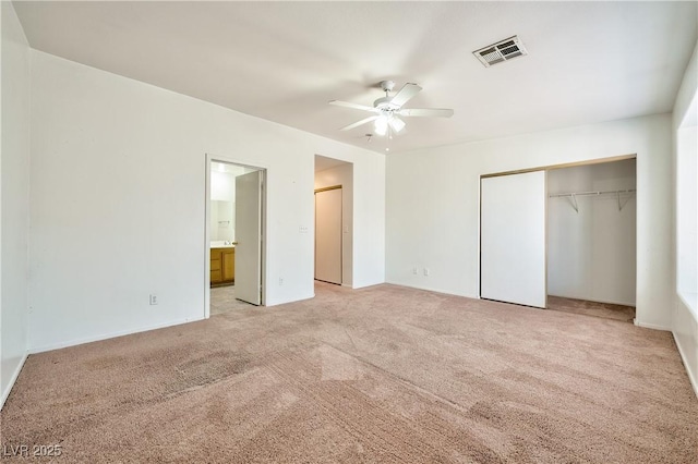 unfurnished bedroom featuring ceiling fan, ensuite bathroom, light carpet, and a closet