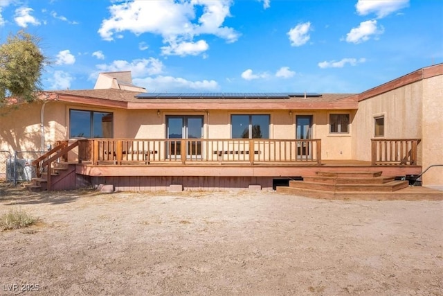 rear view of house featuring solar panels and a deck