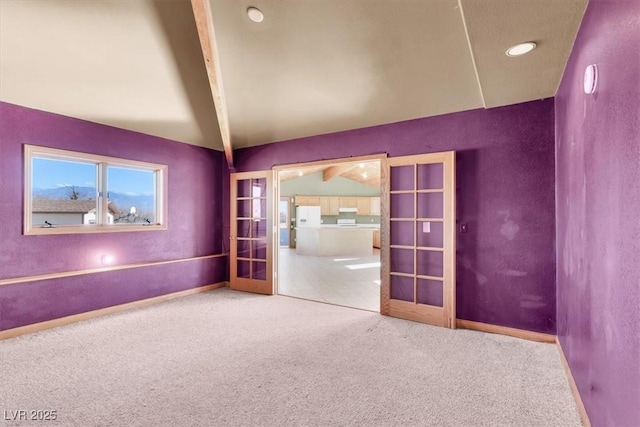 carpeted empty room featuring vaulted ceiling with beams and french doors