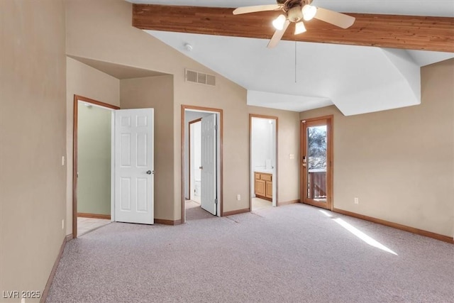 unfurnished bedroom featuring ceiling fan, lofted ceiling with beams, light colored carpet, and ensuite bath