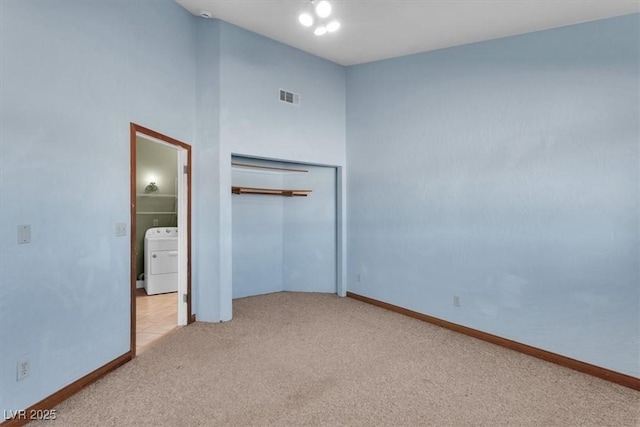 unfurnished bedroom featuring ensuite bathroom, light colored carpet, washer / clothes dryer, and a closet