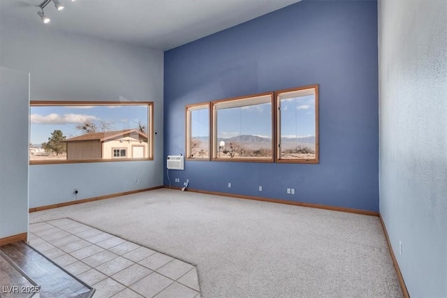 empty room featuring a wall unit AC, light carpet, and track lighting