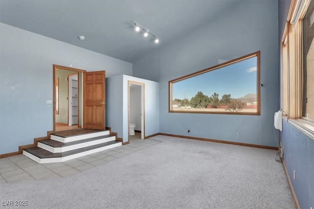 interior space featuring multiple windows, ensuite bath, light colored carpet, and rail lighting