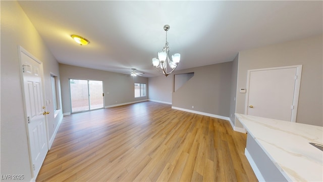 interior space featuring ceiling fan with notable chandelier and light hardwood / wood-style flooring