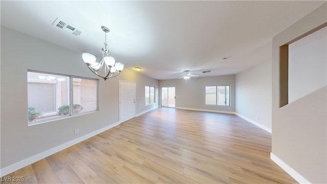 spare room with ceiling fan with notable chandelier, light wood-type flooring, and lofted ceiling