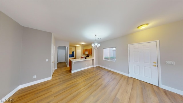 unfurnished living room with a chandelier, light wood-type flooring, and sink