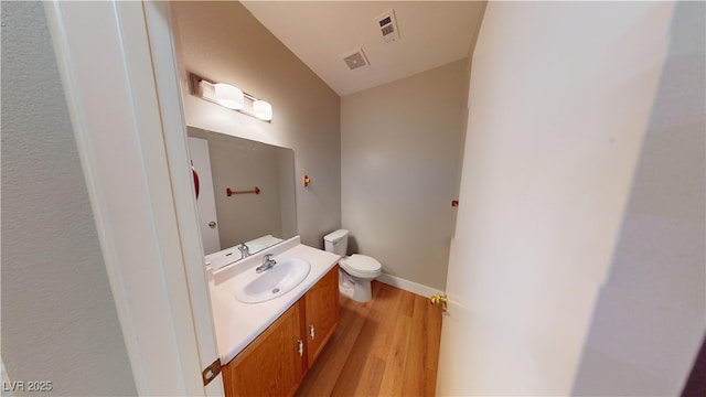 bathroom with wood-type flooring, vanity, and toilet