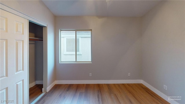 unfurnished bedroom featuring a closet, light hardwood / wood-style floors, and multiple windows